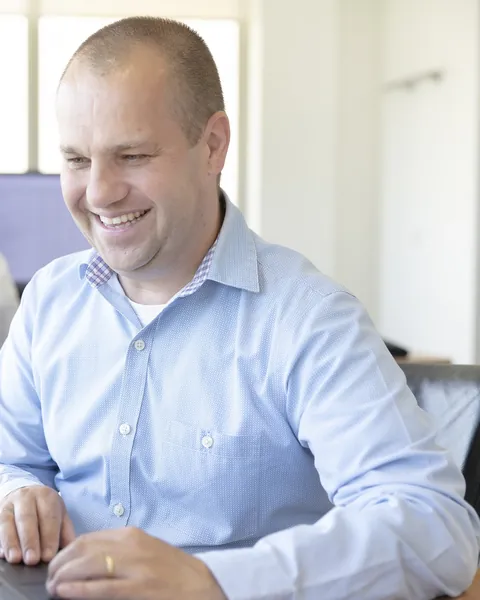 Jeroen van Gerwen lachend achter zijn laptop op kantoor